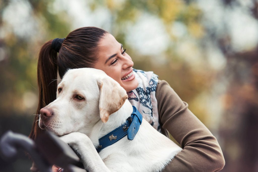 Mujer abrazando un labrador blanco