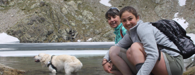 Tractive pet parents Francesca sitting by a lake with her dog, Happy.