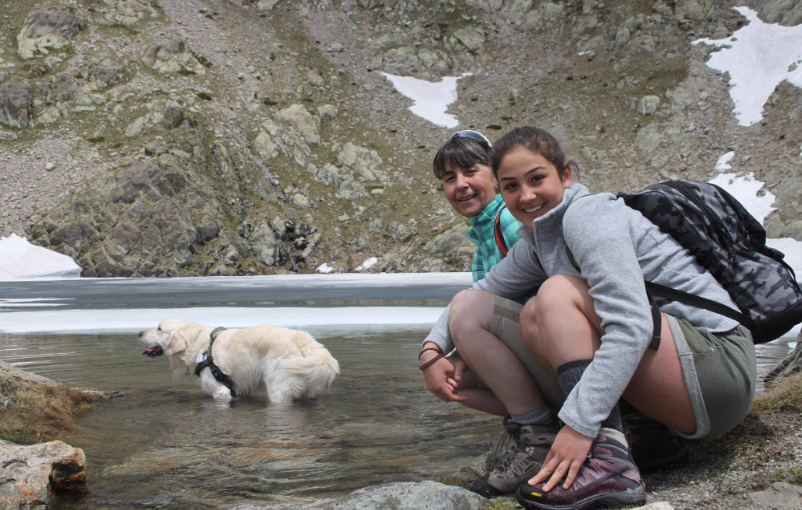 Tractive pet parents Francesca sitting by a lake with her dog, Happy.