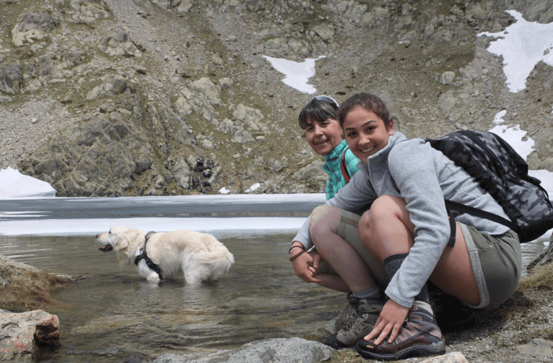 Tractive pet parents Francesca sitting by a lake with her dog, Happy.