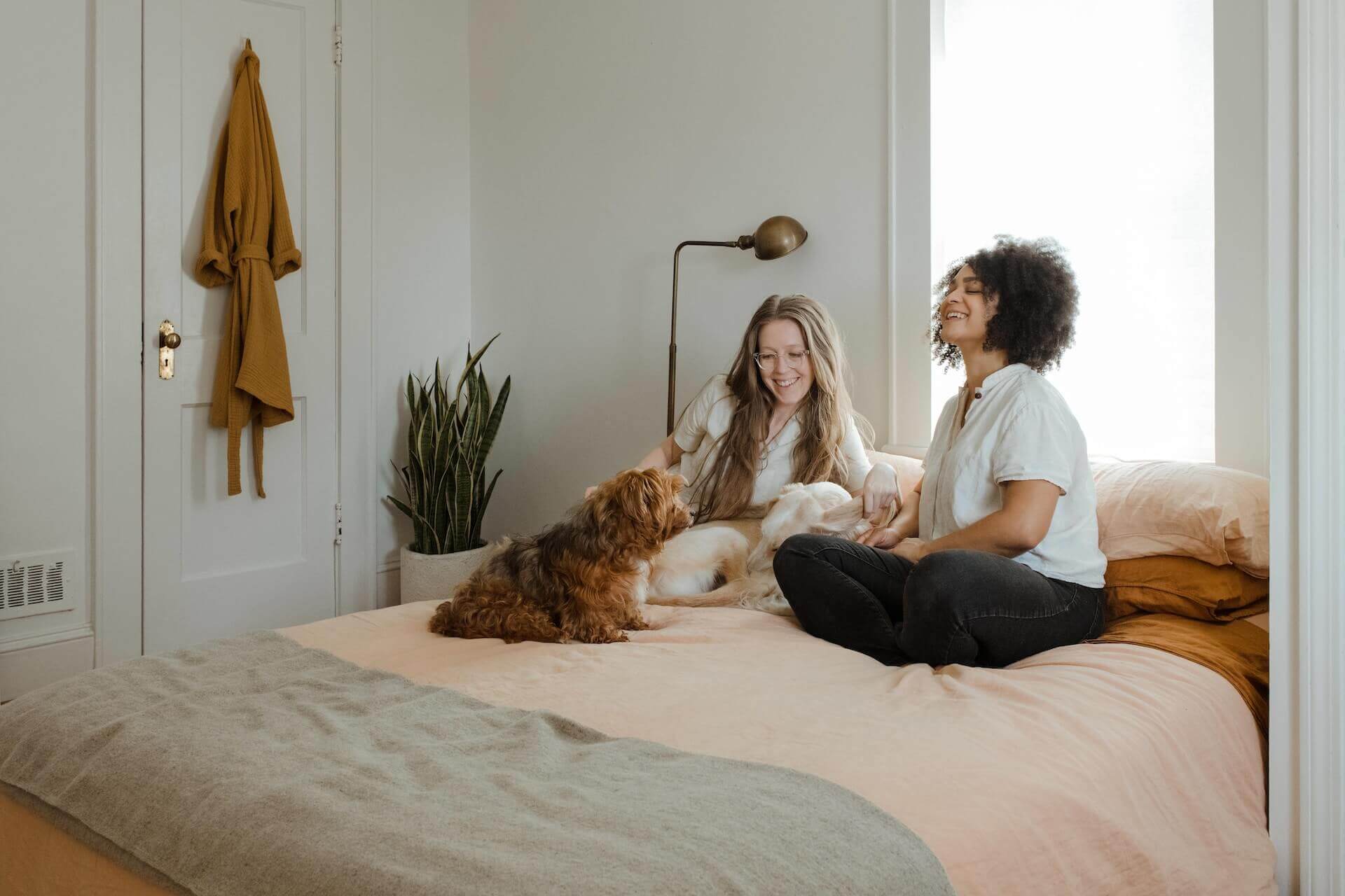 Zwei Frauen sitzen mit einem Hund auf dem Bett