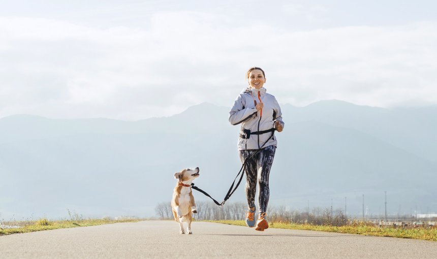 Joggerin läuft mit Hund an der Leine