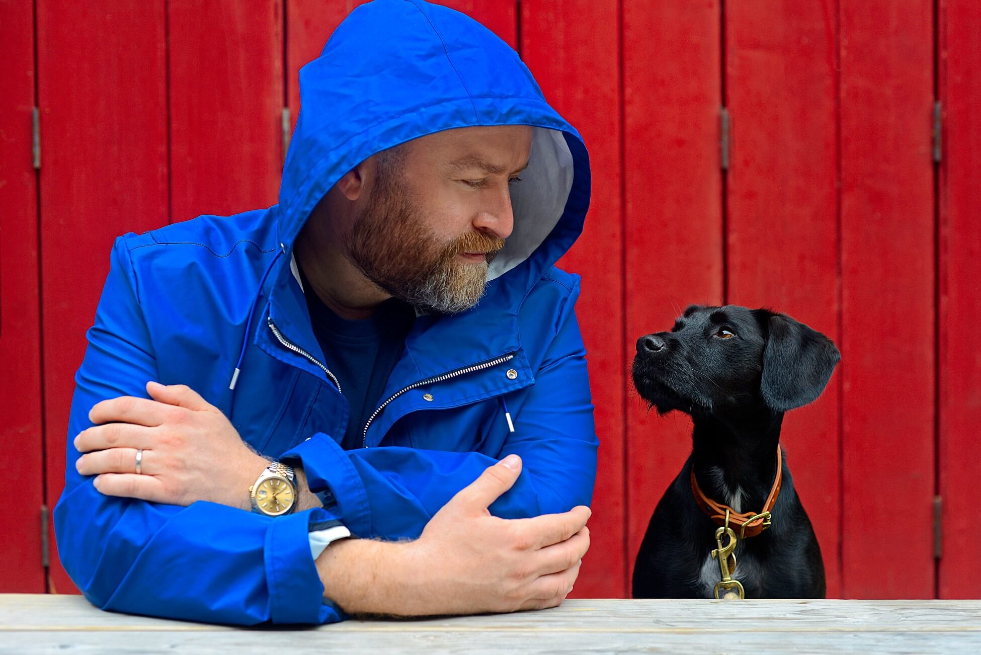 Oli Juste - man in blue coat and black dog with red background bonfire night