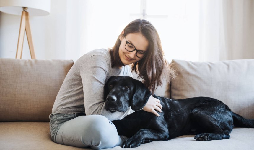 jeune femme et chien noir assis sur le canapé pendant le confinement du coronavirus