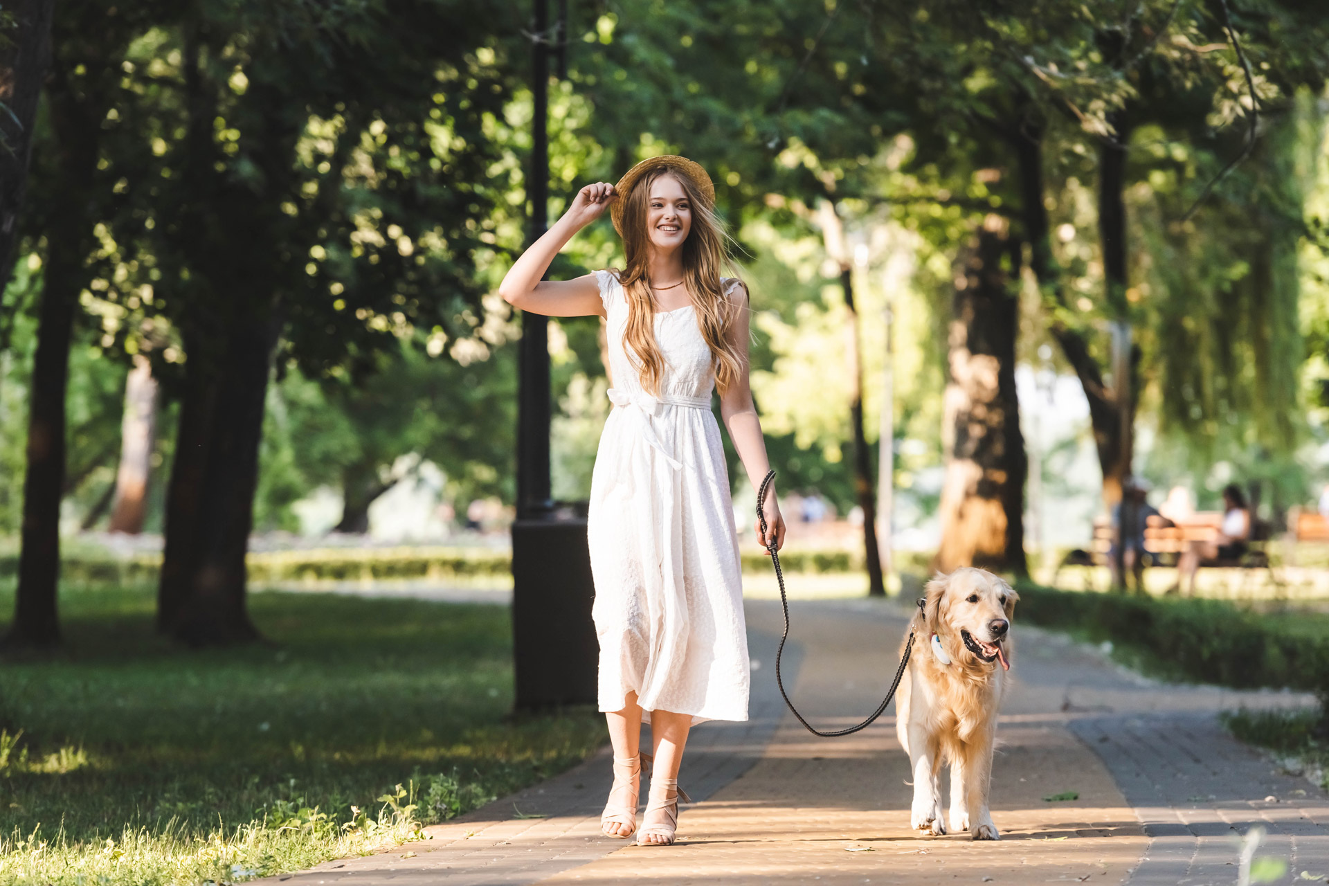 Mujer paseando con perro golden retriever con una correa al aire libre, perro llevando el Localizador GPS para perros de Tractive