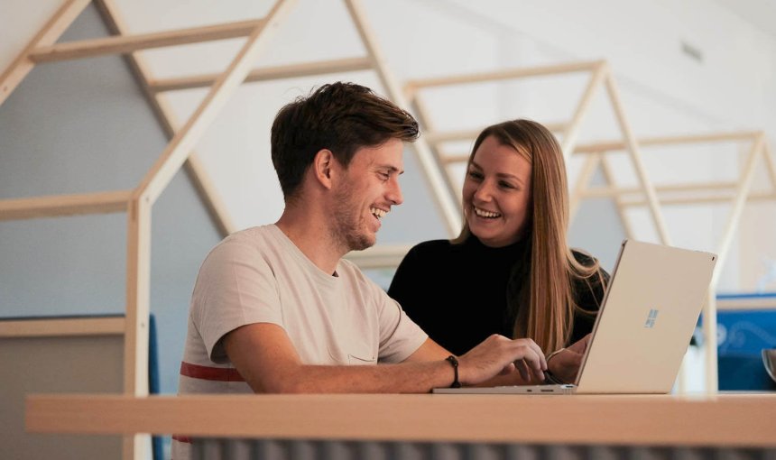 man and woman talking over a computer in a modern office