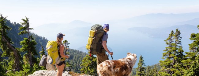 Deux personnes avec sac a dos en randonnée avec leur chien