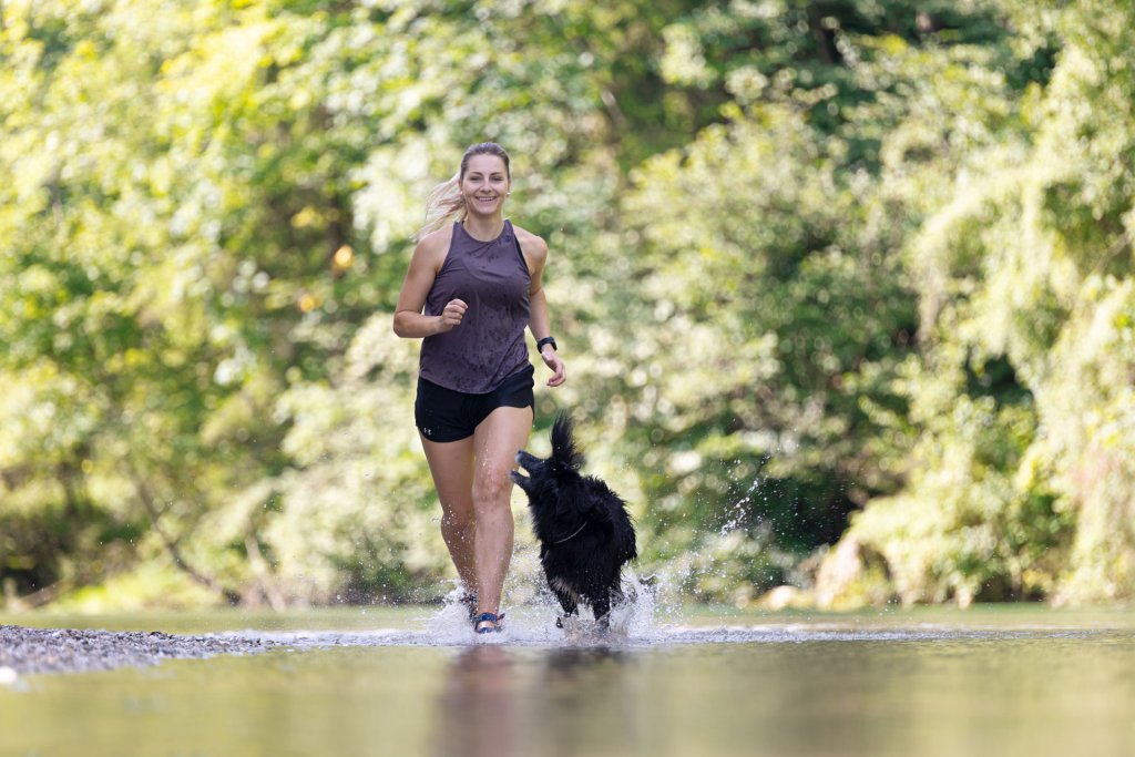 Mujer y perro corriendo en un río