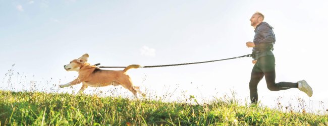 uomo corre all'aperto portando un cane al guinzaglio