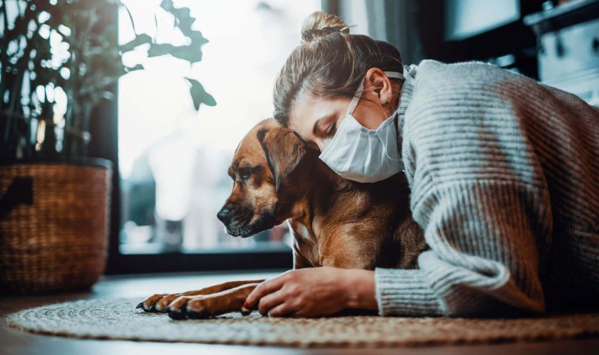 femme portant un masque couchée sur un tapis avec son chien