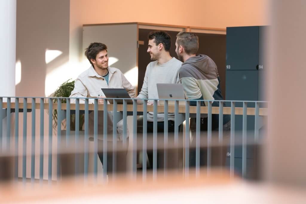 three men talking in an office