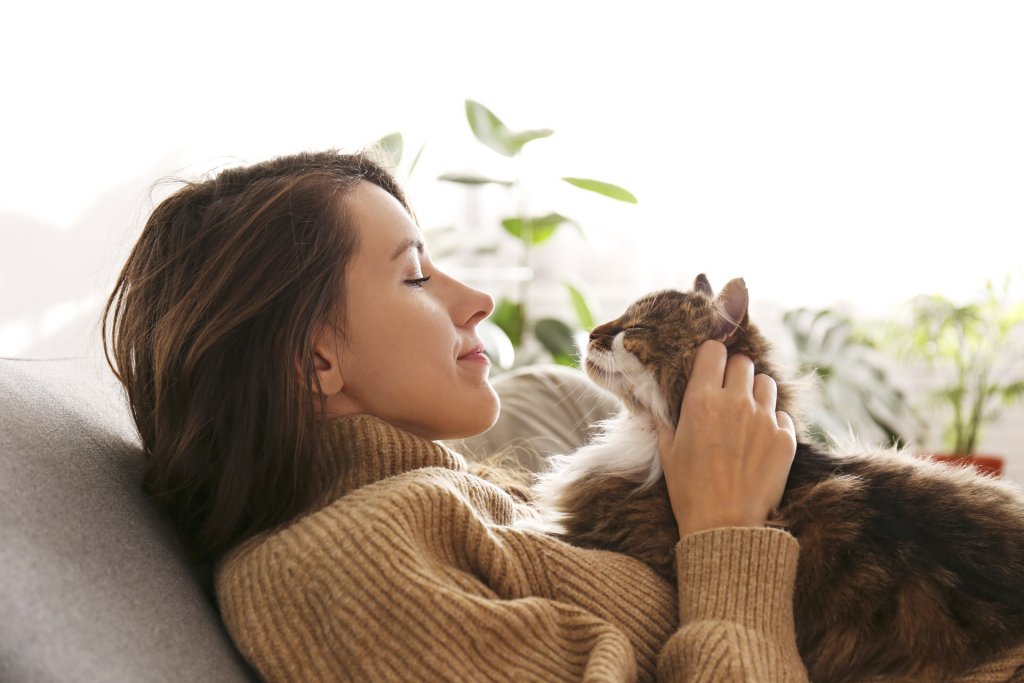 jeune femme inclinée sur un sofa, caressant un chat couché sur sa poitrine