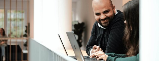 man and woman working at computers talking in an office