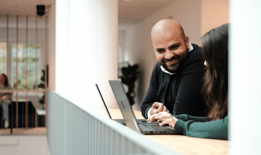 man and woman working at computers talking in an office