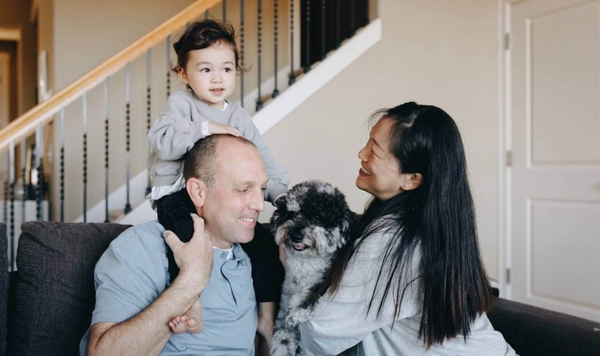 man woman, child and dog sitting on a couch