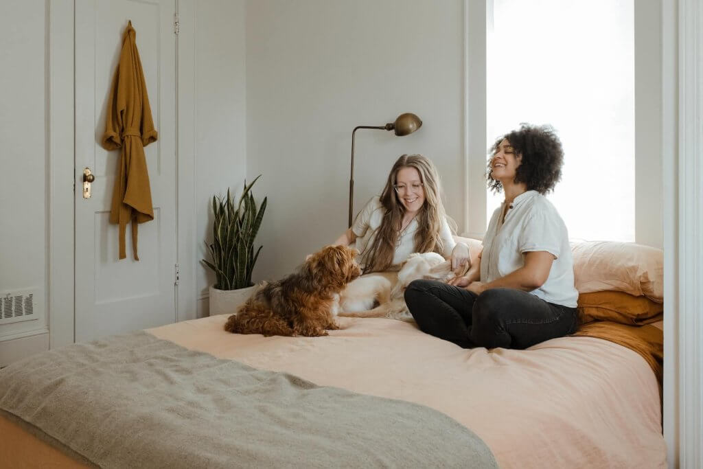 deux jeunes femmes avec deux chiens, tous assis sur un lit