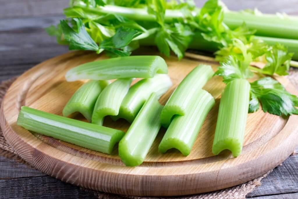 céleri branche sur une planche coupé en morceaux pour qu'un chien puisse le manger