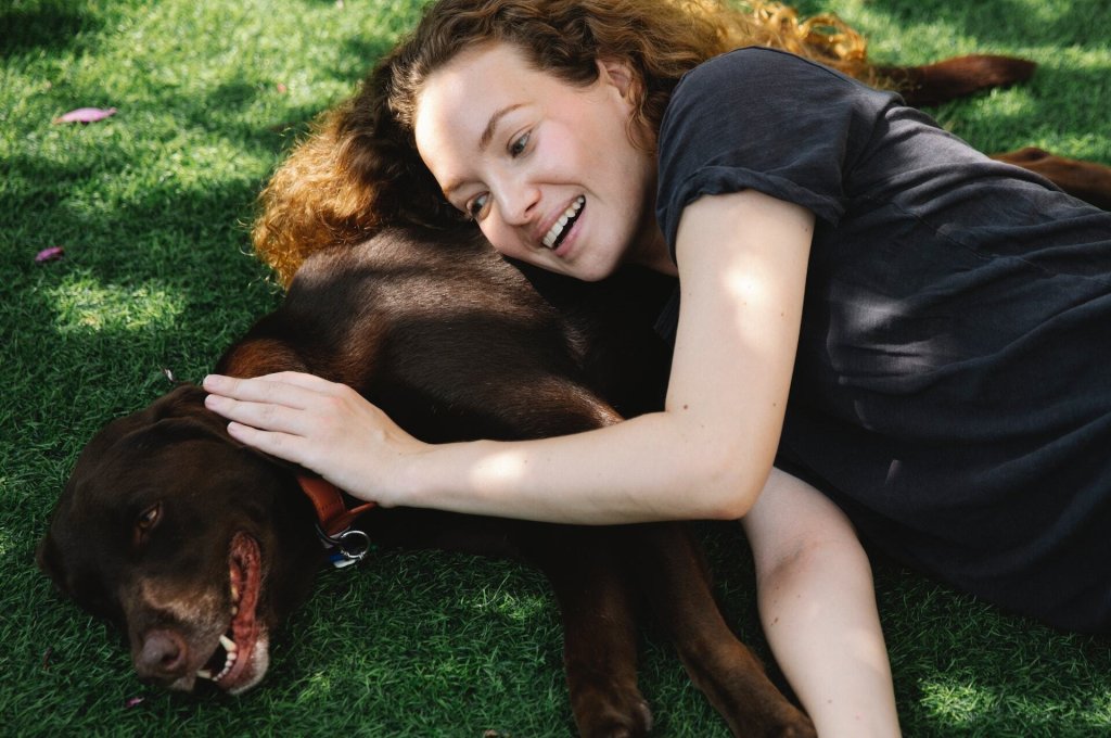 A woman praises her dog by patting their head