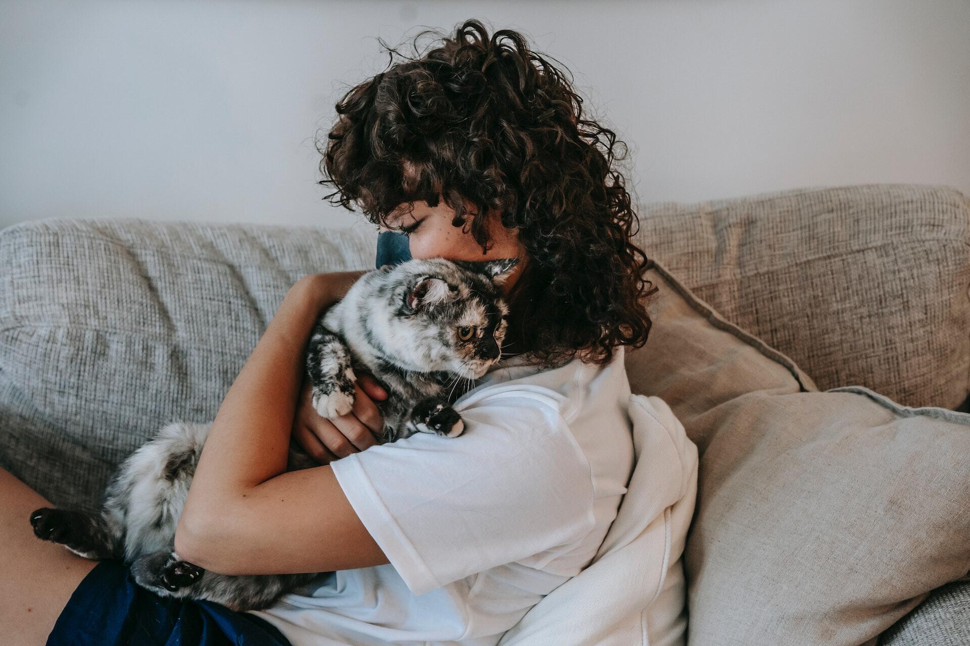 A woman hugging her cat on a couch