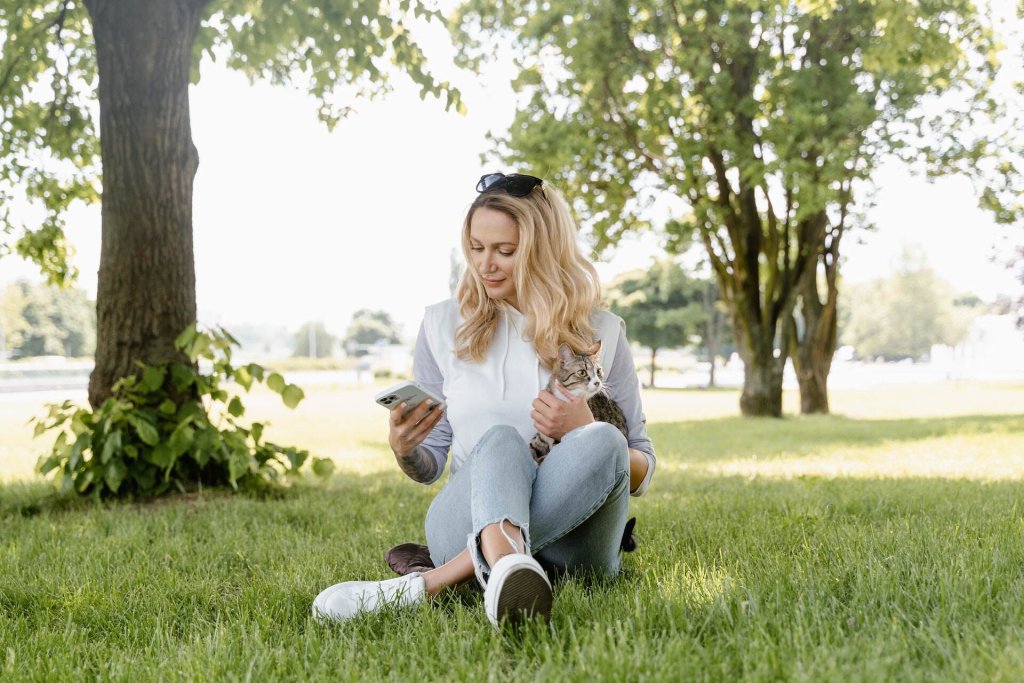 A woman relaxing with her cat outdoors in a park