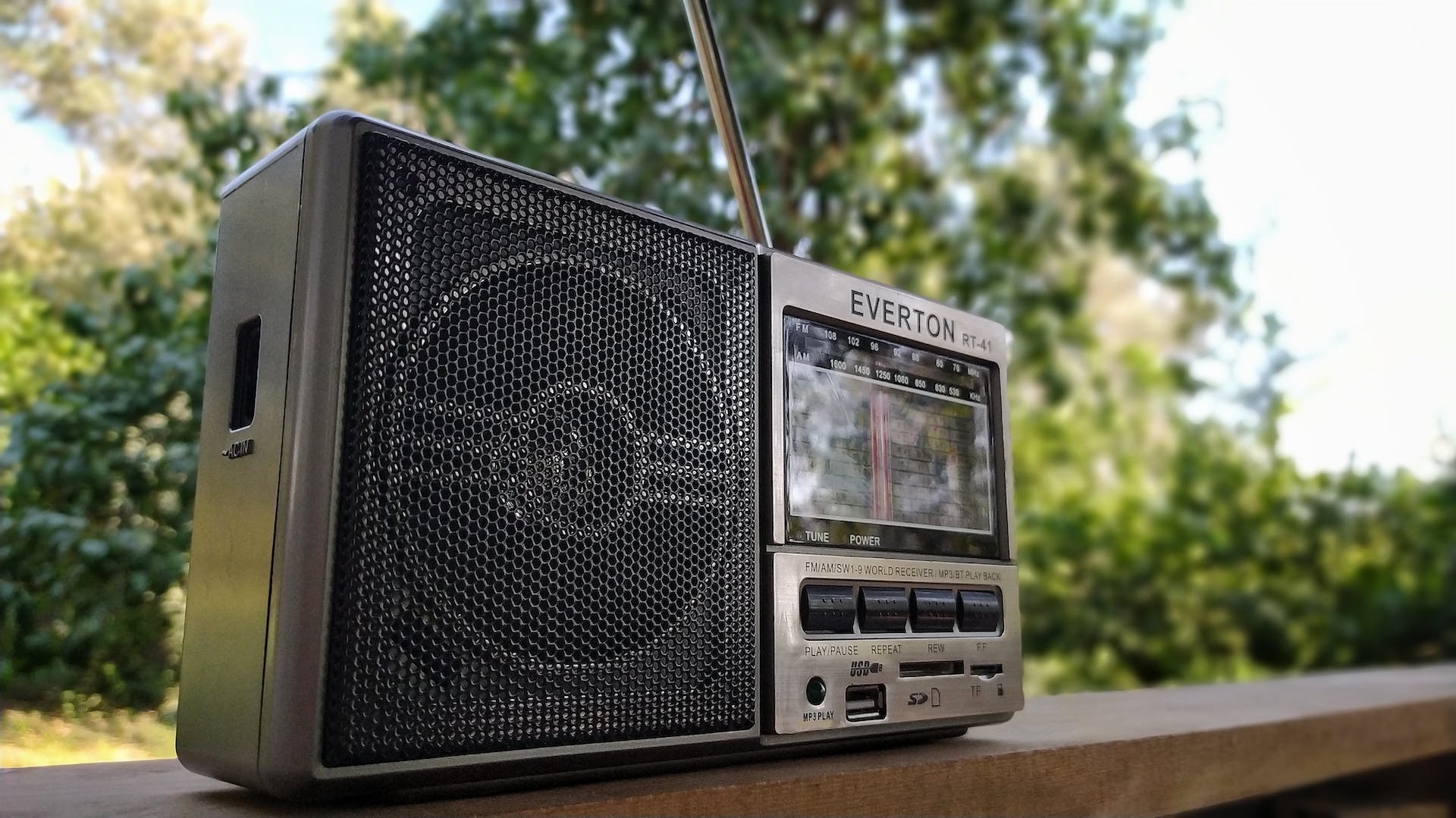 A radio placed on a wooden shelf outdoors