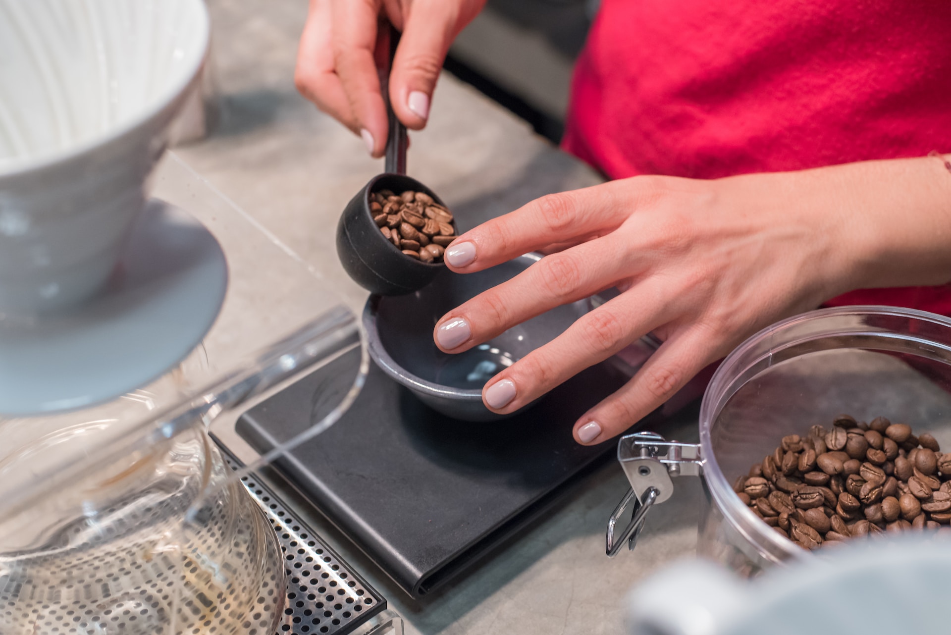 A woman measuring out coffee grounds with a food scale