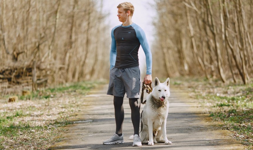 Hardloper met hond tijdens een wandeling in het bos