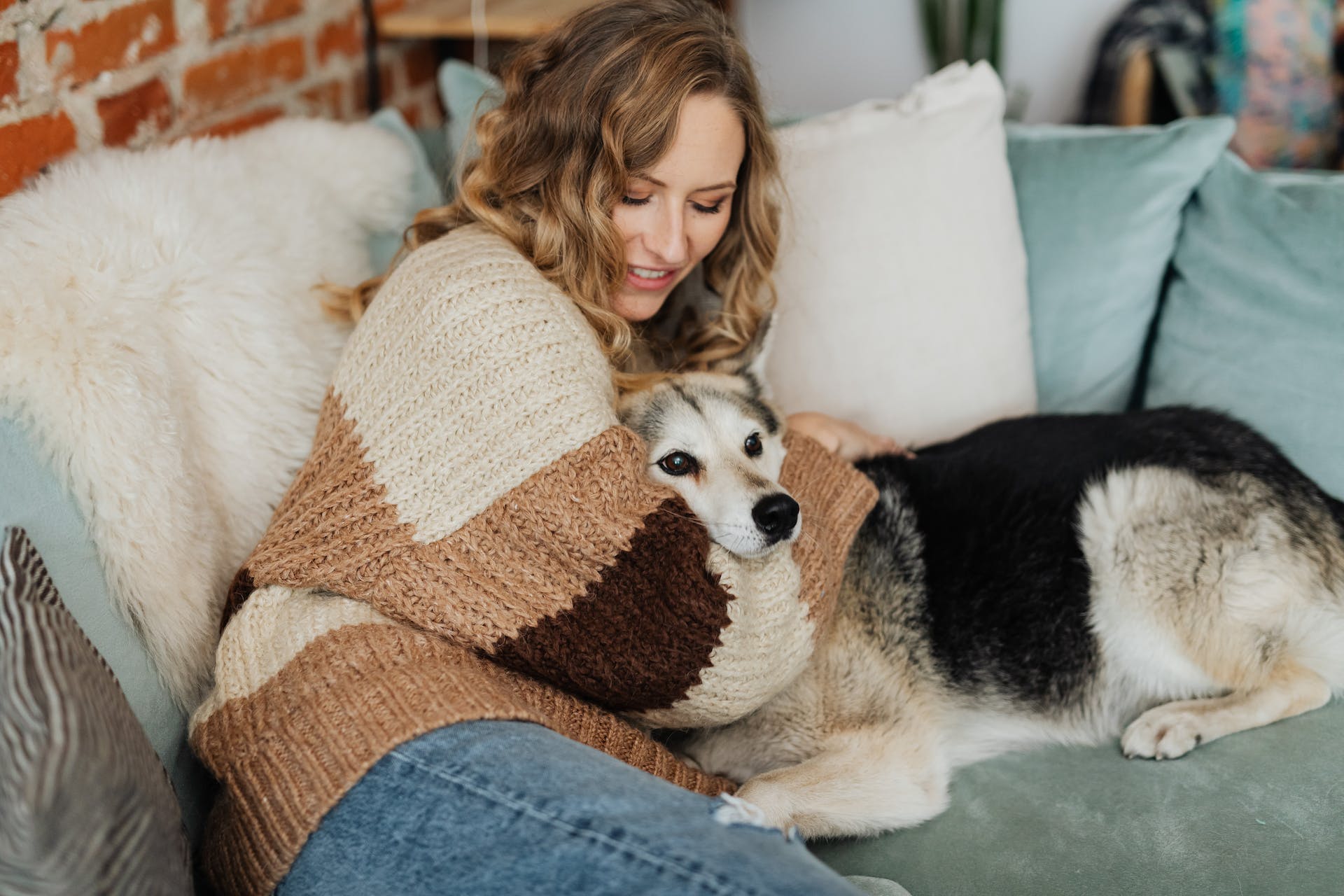 jeune femme blonde assise sur un canapé. tenant un chien dans ses bras