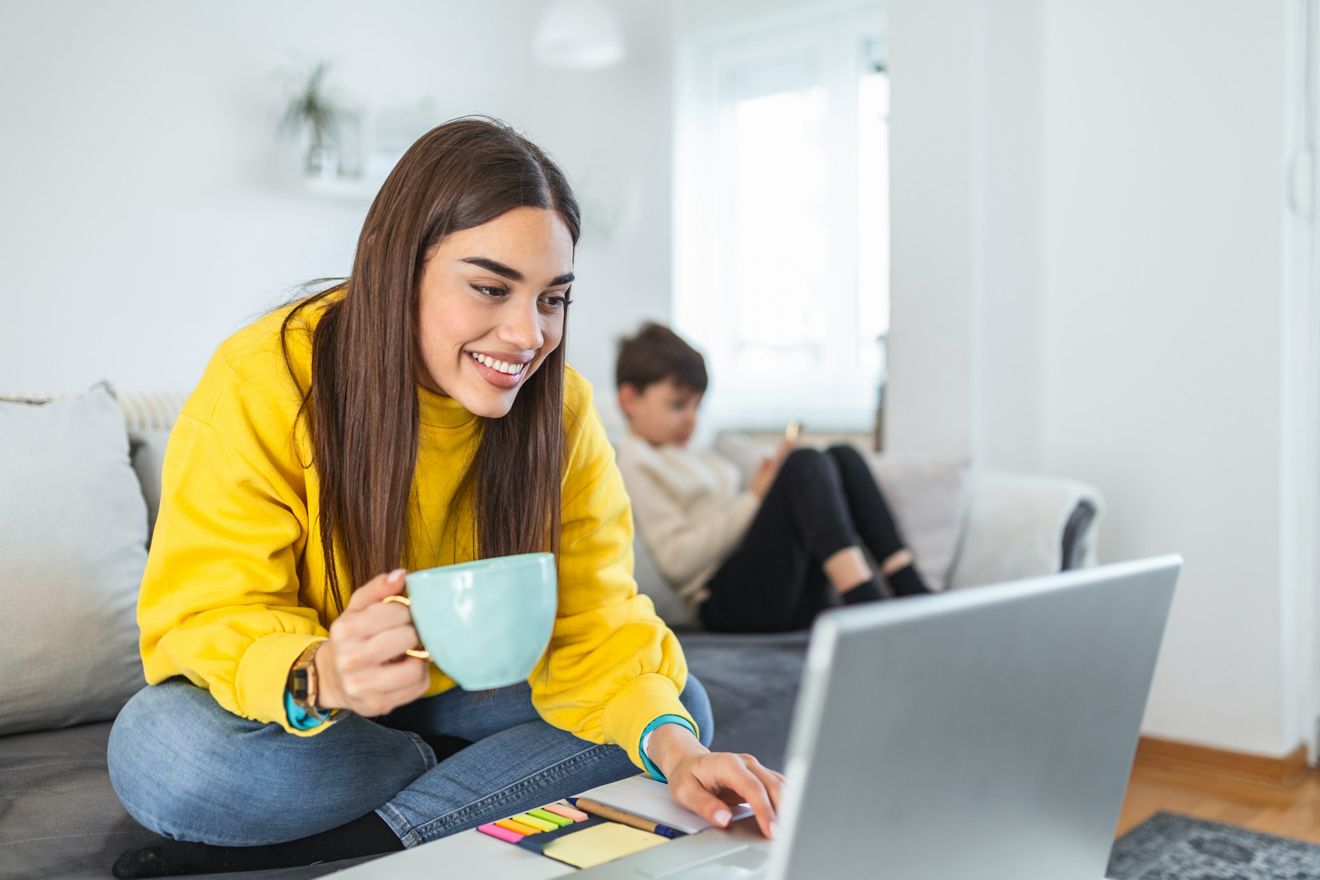 A woman wearing a yellow sweater checking her laptop