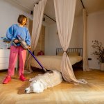 A woman vacuuming her dog at home