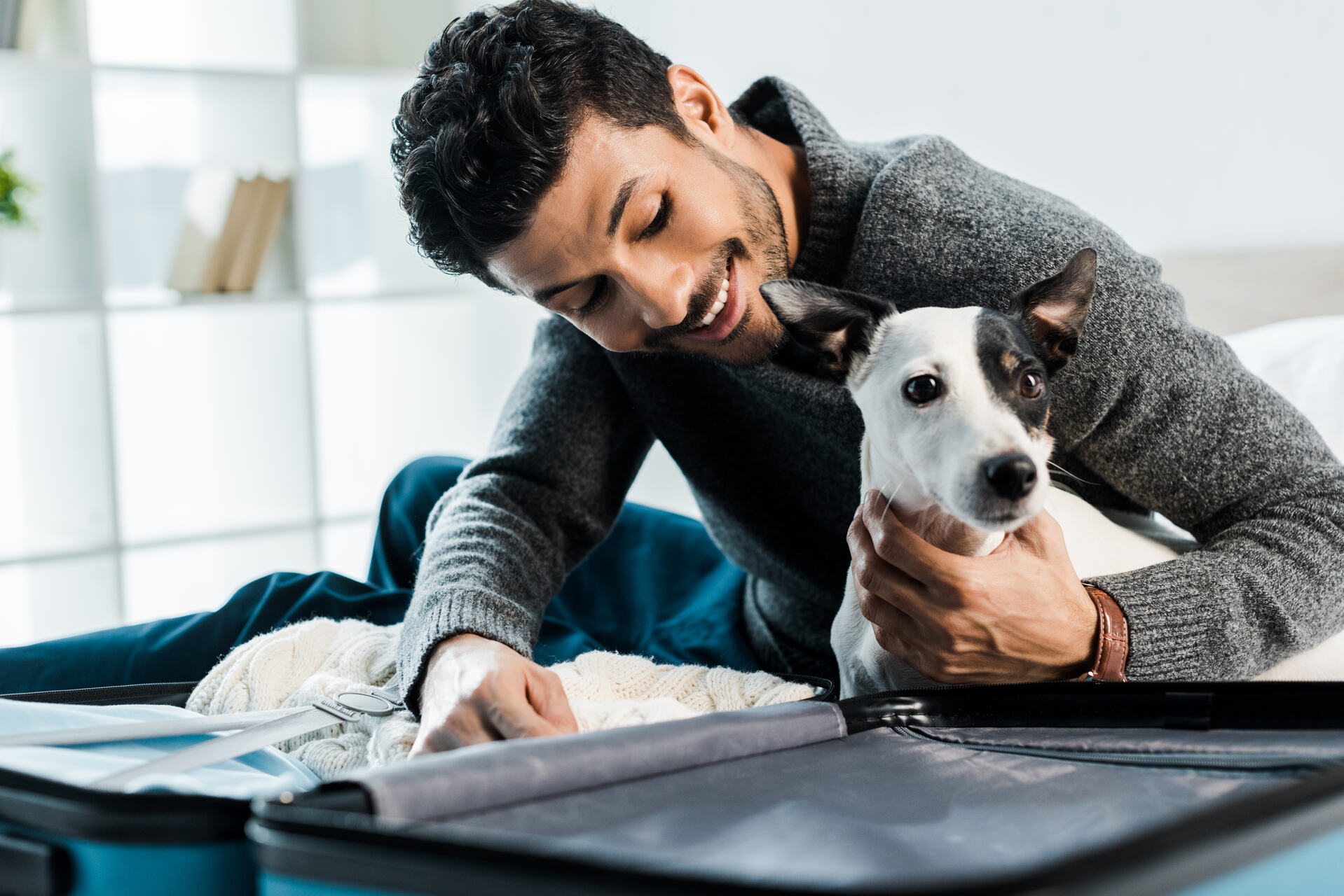 A man packing his suitcase next to his dog