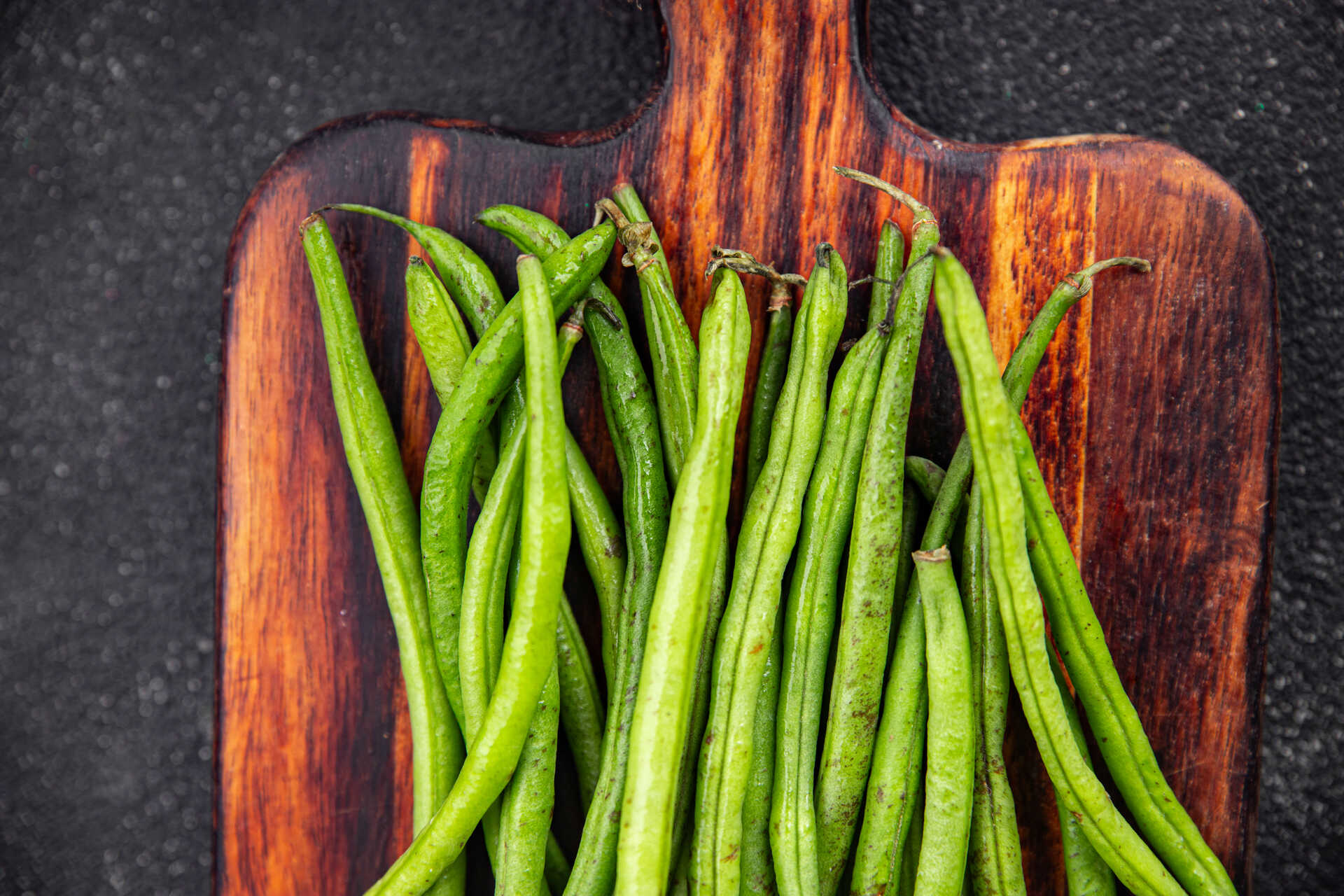 A pile of green peas lying on a wooden cutting board