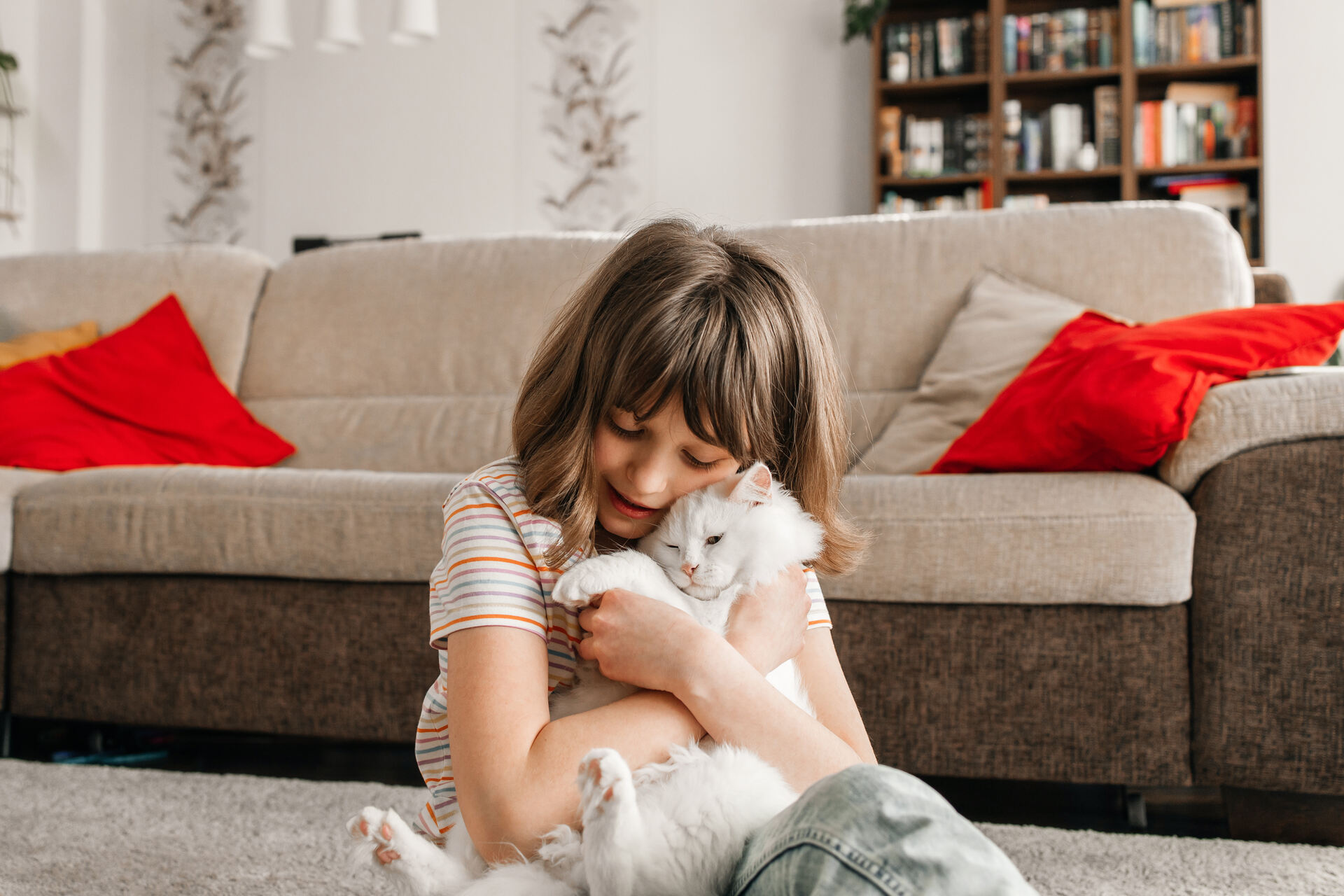 A young girl hugging a white cat