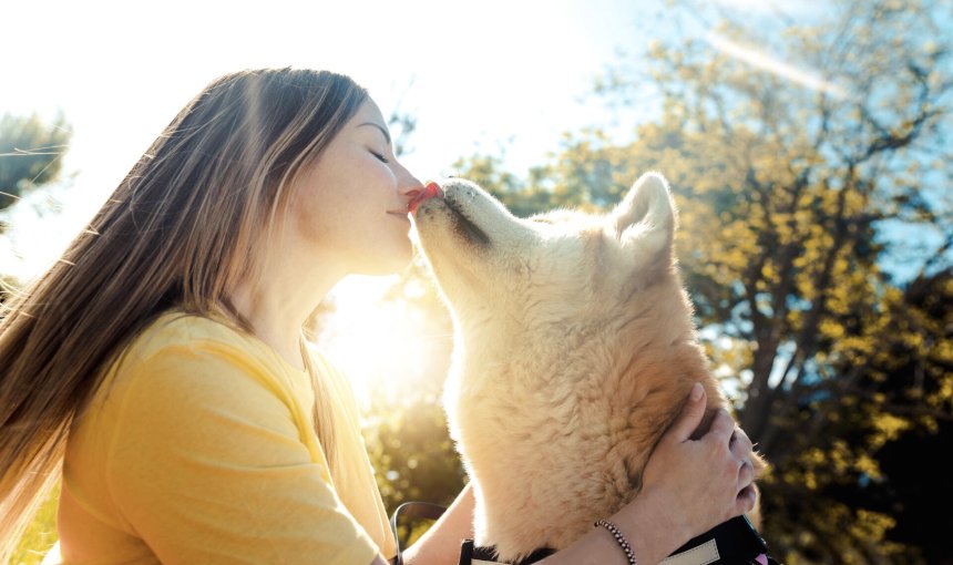 A woman kissing her dog on a sunny day