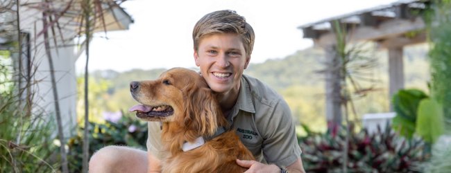 Robert Irwin cuddling a dog with a Tractive tracker in a garden