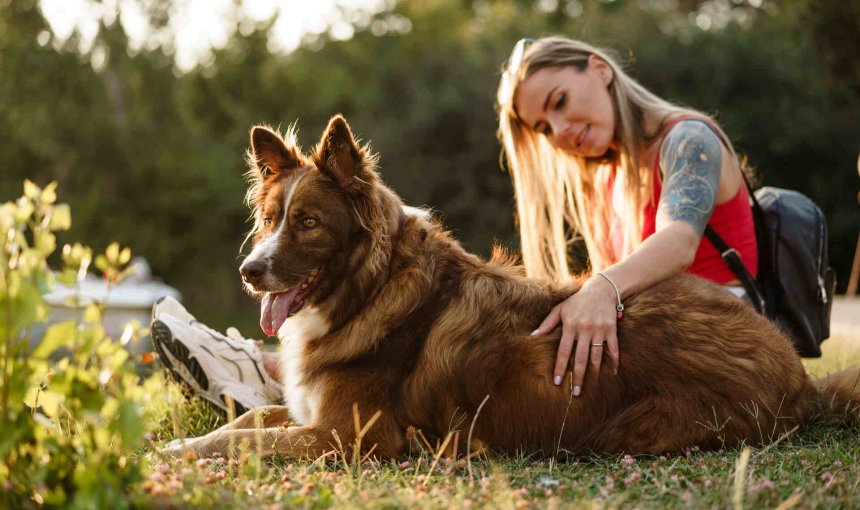 A young woman sitting with her dog at a park